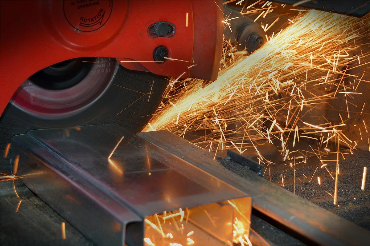 An angle grinder cutting a steel section, throwing sparks.