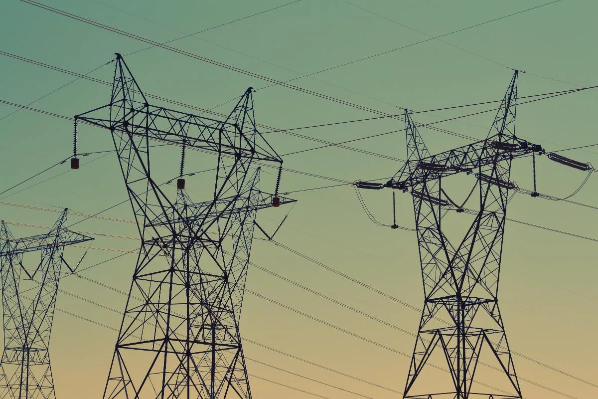 Electricity pylons and power lines against a dusk sky.