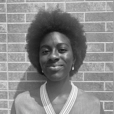 Portrait of a woman standing in front of a brick wall.