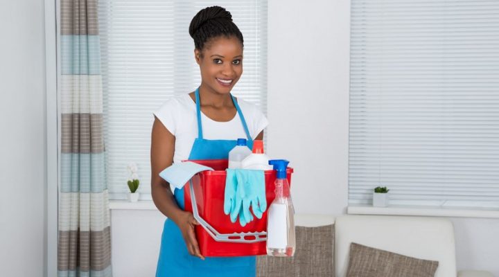 50691540 - smiling african woman holding basket with cleaning equipment